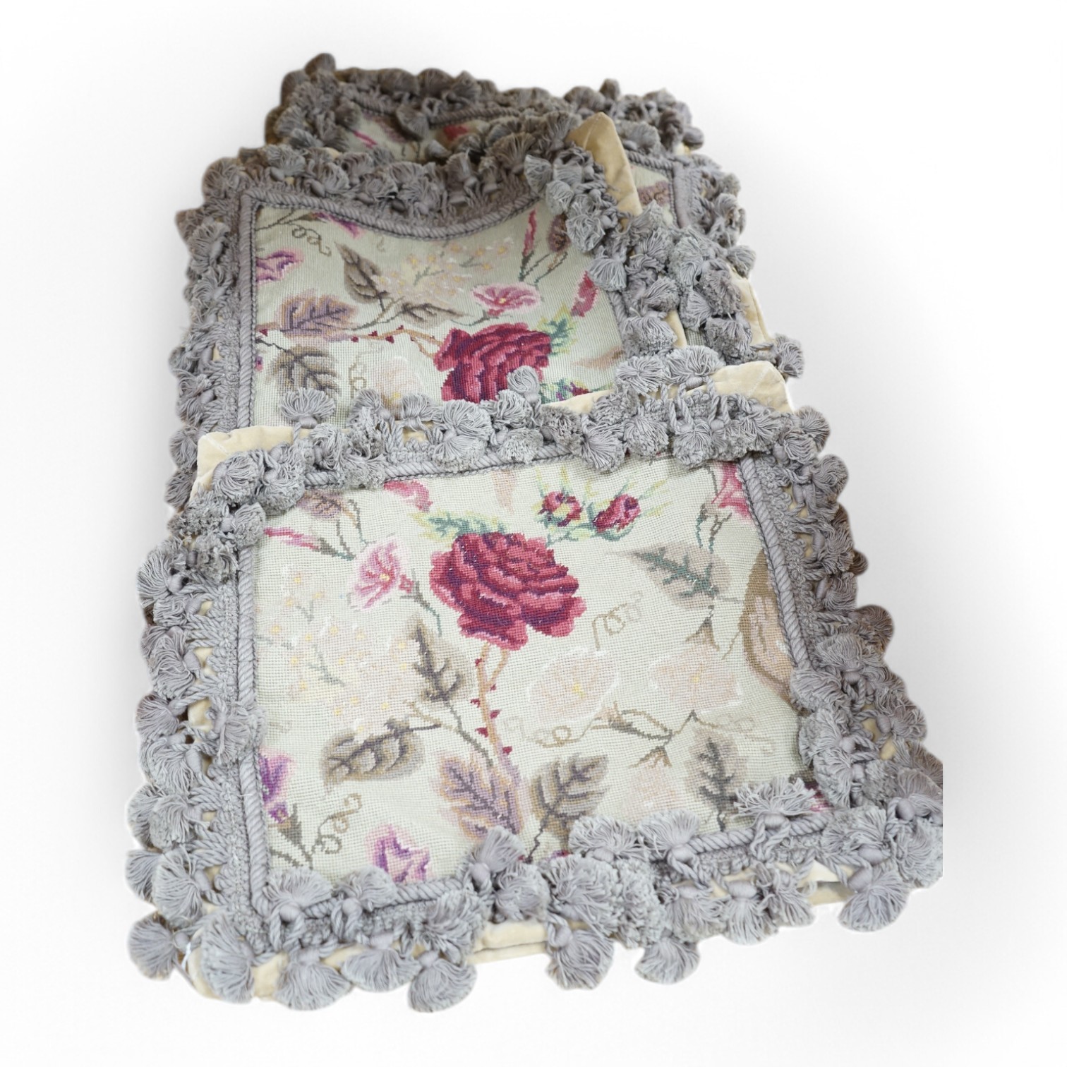 Six small wool worked rectangular cushion covers, designed with roses and trailing flowers on a pale green ground, with mushroom tasselled fringing and velvet backs. 30cm wide x 26cm high. Condition - unused